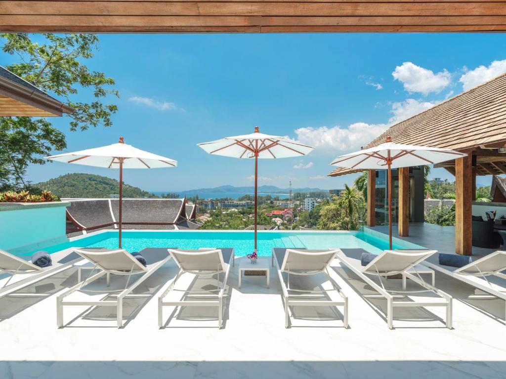 a view of a pool with chairs and umbrellas at Baan View Talay - Sea View Zenith Villa By Elite Havens in Surin Beach