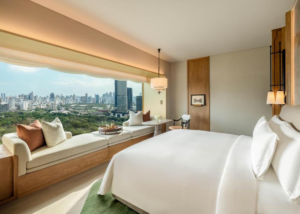 A spacious bedroom with a large bed, window bench, and panoramic city view.