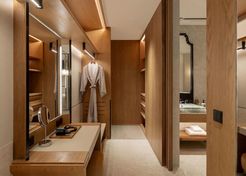 A timber-lined dressing and wardrobe area with a compact vanity desk, mirror and bathrobe.
