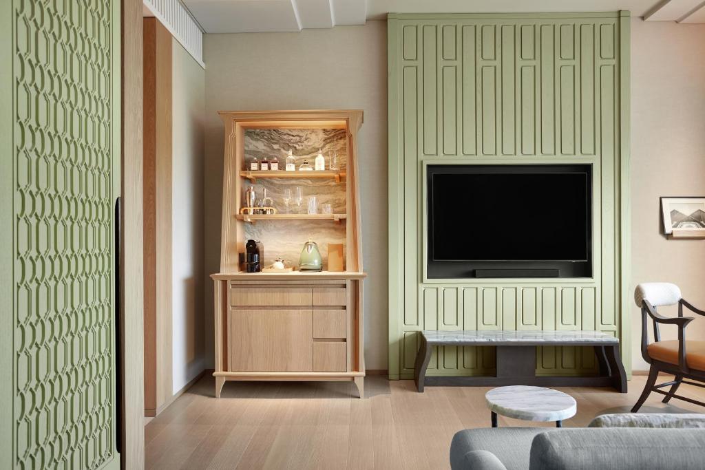 A sitting area with a wall-mounted television, drinks cabinet, and lounge chair.