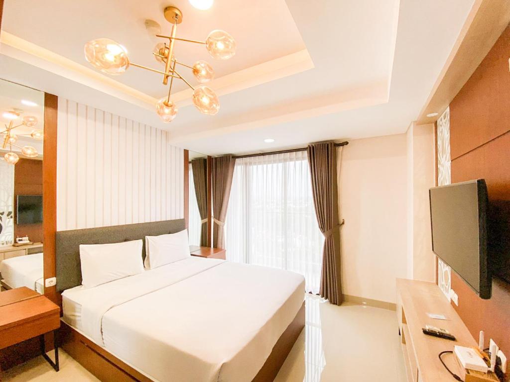 a bedroom with a bed and a desk and a television at Good and Restful Studio at Patraland Amarta Apartment By Travelio in Kejayan