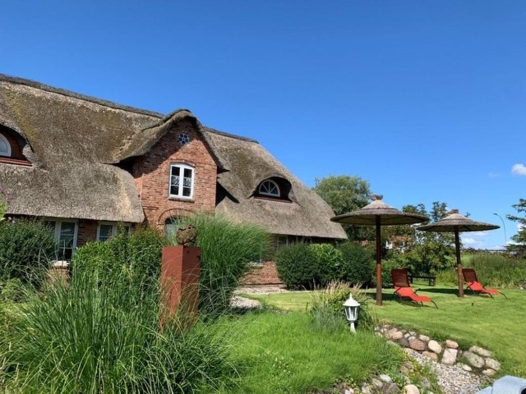 a thatch roofed house with a garden in front of it at Fewo ODIN by fewo-plan GALM100 an der Nordsee bei Dagebüll in Galmsbüll