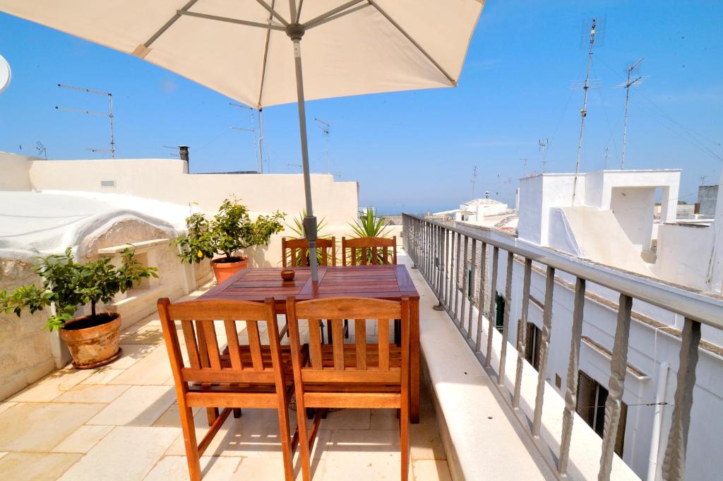 einen Tisch und Stühle auf einem Balkon mit Sonnenschirm in der Unterkunft Casa Antica Roma in Ostuni