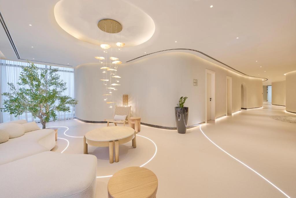 eine Lobby mit weißen Möbeln und einem Kronleuchter in der Unterkunft The OQ in Doha