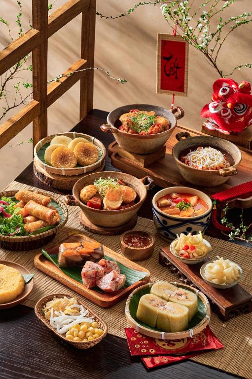A large spread of Asian-inspired dishes arranged on a wooden table.