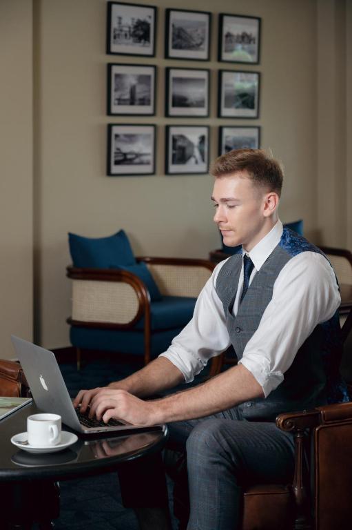 A guest works on a laptop from a lounge chair beside a small round table.