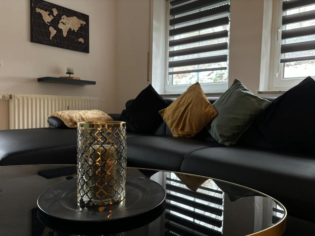 a living room with a black couch and a table at FeWo Wiehl-Marienhagen, Modern, ruhig, ländlich in Wiehl