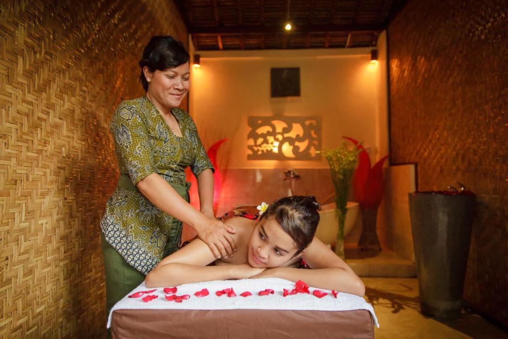 a woman standing next to a woman laying on a bed at Liyer Spirit House in Ubud