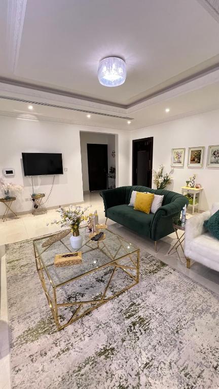 Una sala de estar con un sofá verde y una mesa. en شقة غرفتين نوم وصالة وحديقة خارجية, en Riad