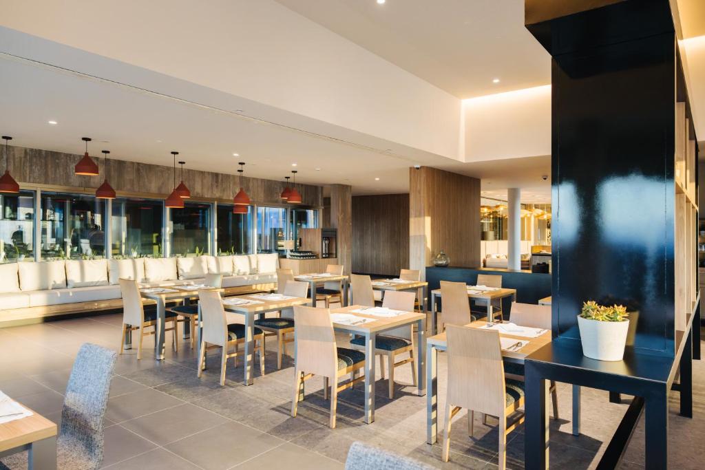 a restaurant with tables and chairs and windows at BANCAL HOTEL and SPA in San Sebastián de la Gomera