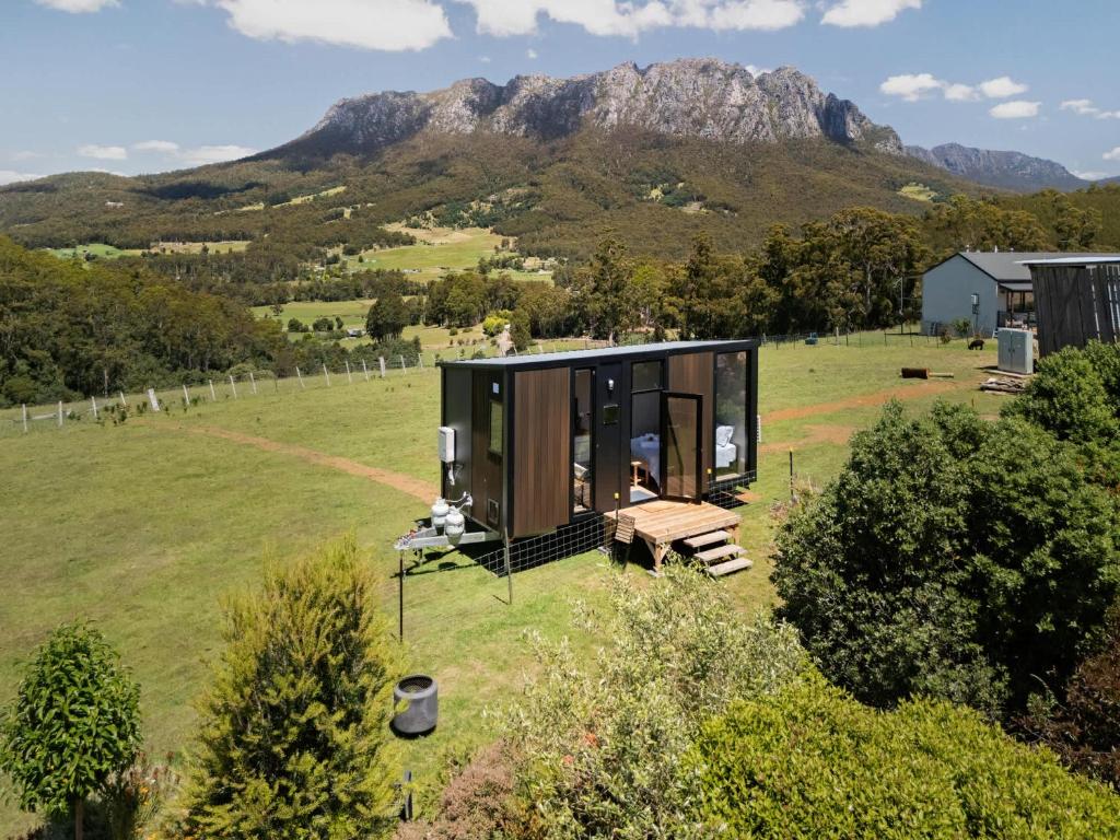 a house in a field with a mountain in the background at Hillside Hideout by Tiny Away in West Kentish