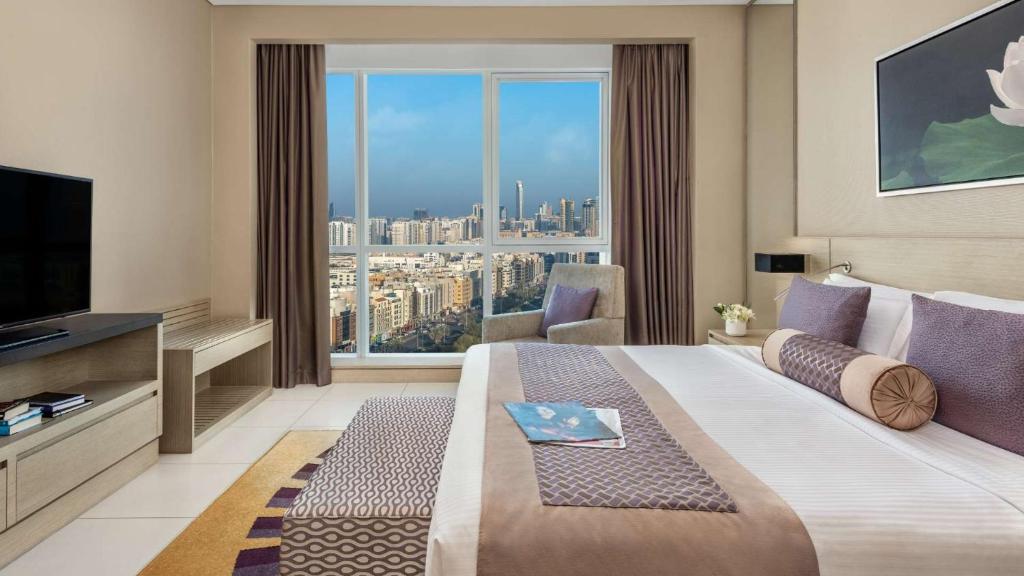 a hotel room with a large bed and a large window at Dusit Thani Abu Dhabi in Abu Dhabi