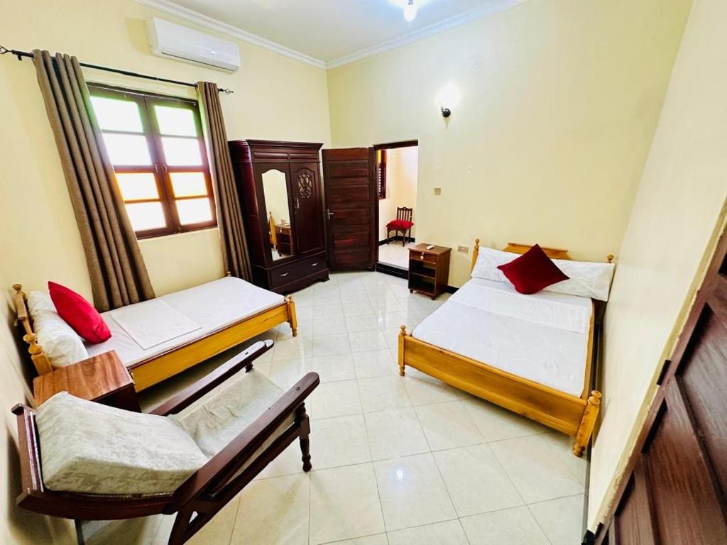 a room with two beds and a chair in it at Vuga Hostel in Zanzibar City
