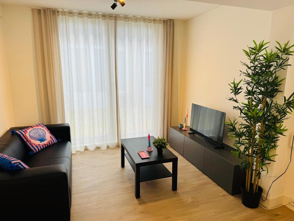 Una sala de estar con un sofá, un televisor y una mesa. en Zomerhuis - Gratis parkeren!, en Noordwijk aan Zee