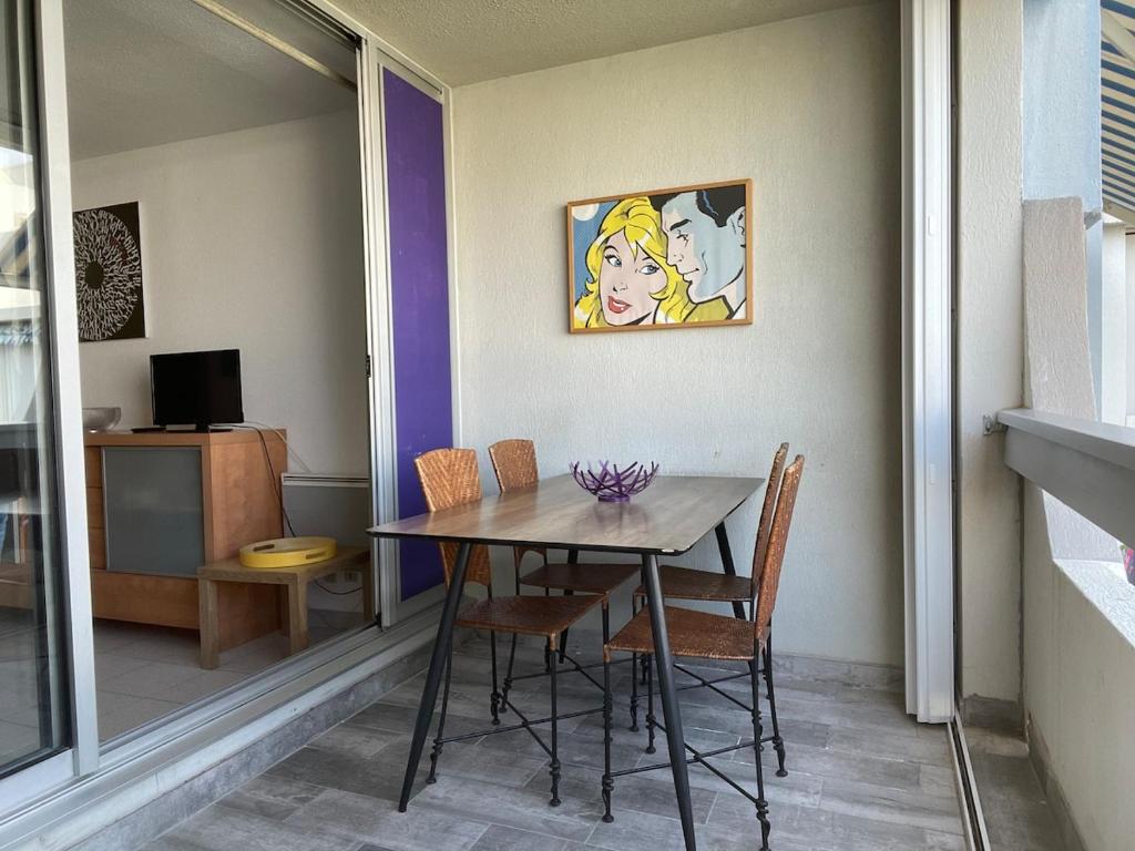 une table de salle à manger avec des chaises et un tableau au mur dans l'établissement Studio Grau du Roi 5 min plage, au Grau-du-Roi
