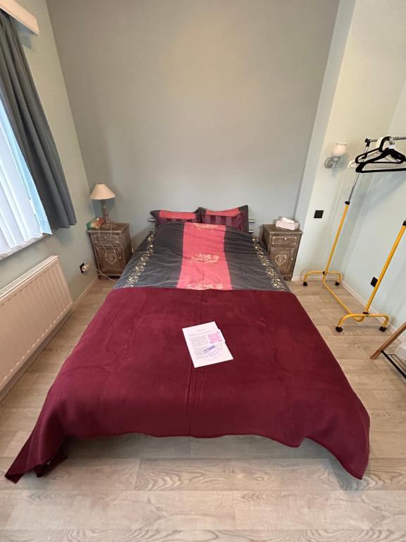 una camera da letto con un grande letto con una coperta rossa di Chambre dans habitat partagé chez Séverine a Nivelles