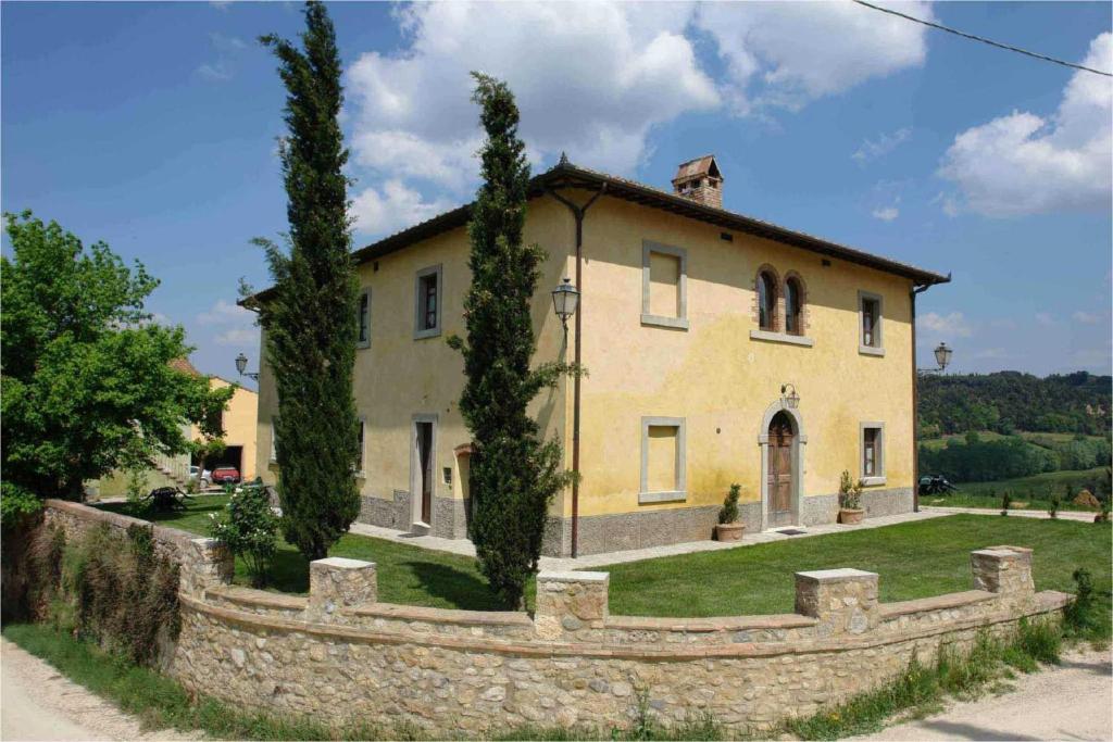 ein großes gelbes Haus mit einem Steinzaun in der Unterkunft Tenuta Il Tresto in Poggibonsi
