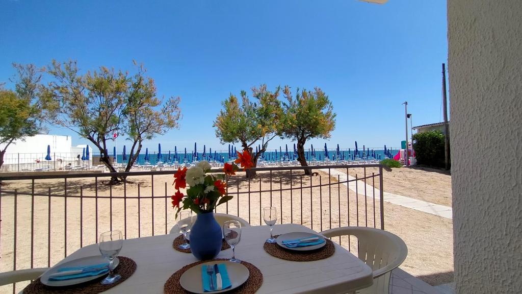 a table with a vase of flowers on a beach at P313 nr 102 trilocale sul mare con ombrellone in prima fila in Marcelli
