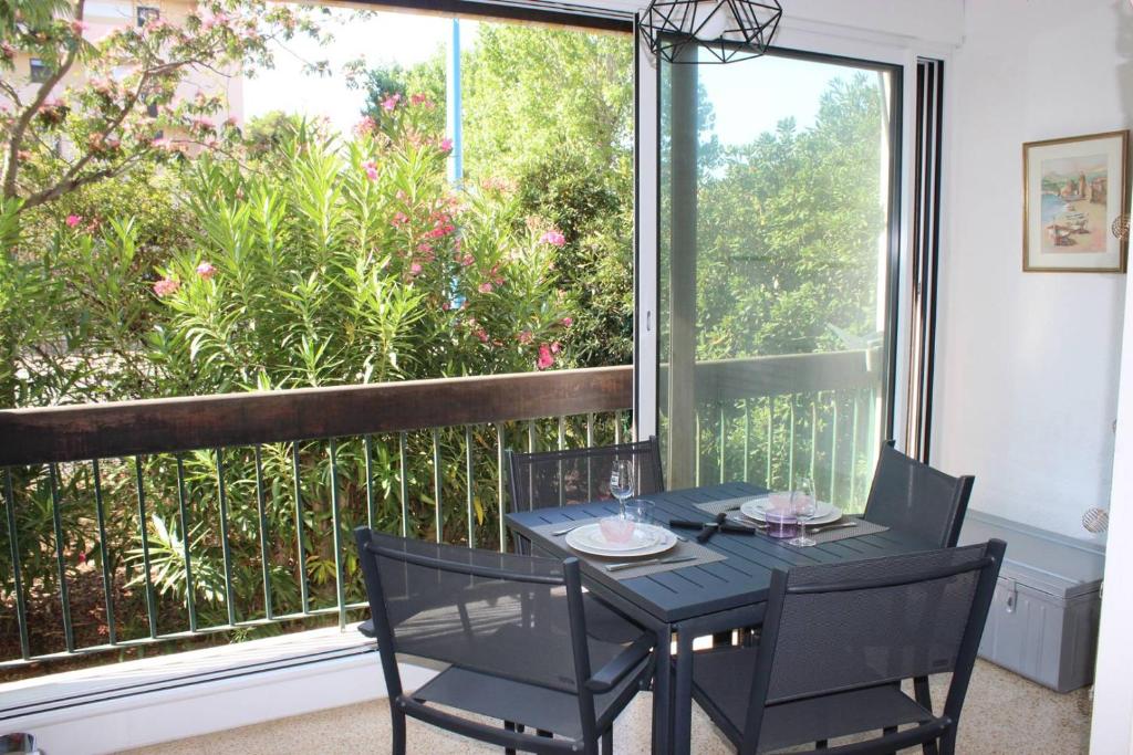 une table et des chaises sur un balcon avec une grande fenêtre dans l'établissement Spacieux T2 avec parking privatif proche du Port et de la plage-4RM217, à Saint Cyprien Plage