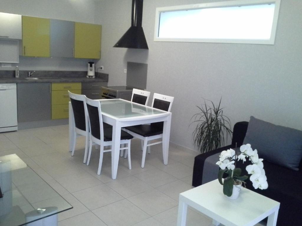une cuisine et un salon avec une table et des chaises blanches dans l'établissement Appartement T2 tout équipé, à Le Fauga