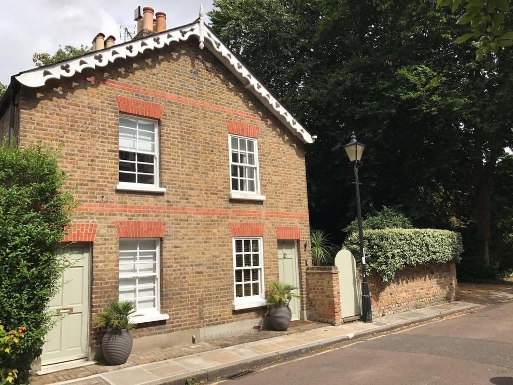 ein rotes Backsteinhaus mit weißen Fenstern und einem Straßenlicht in der Unterkunft Charming Cottage with Roof Terrace in Twickenham