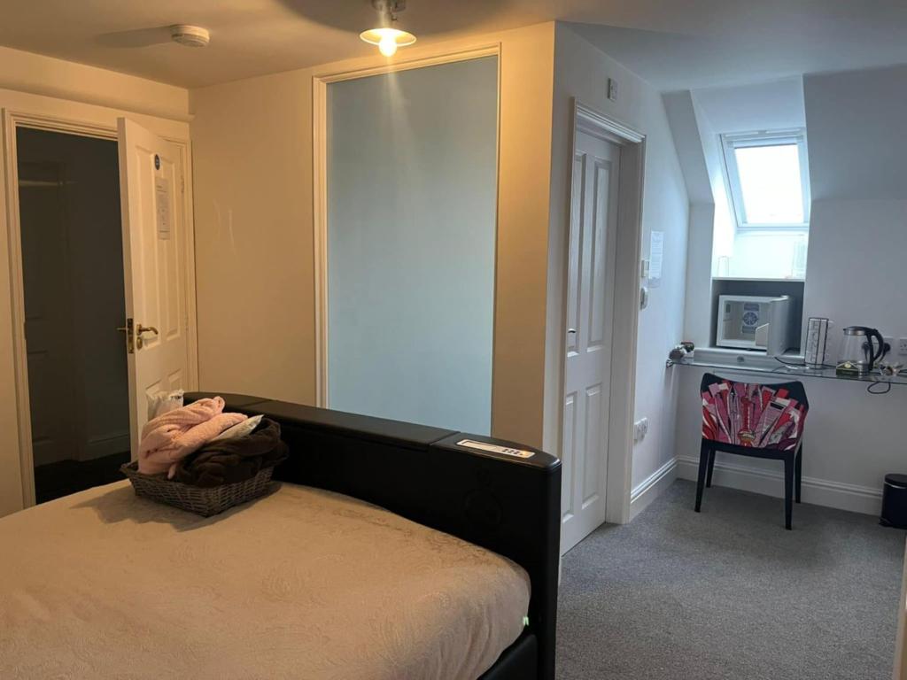 a bedroom with a bed and a chair and a window at Elysian Fields B&B in Helston