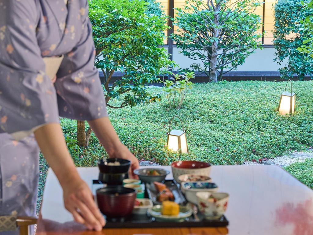 a woman standing in front of a table with a tray of food at Hotel Nikko Kumamoto in Kumamoto