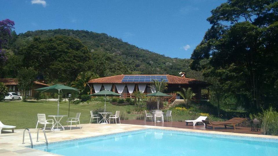 a house with a swimming pool in front of a house at Pousada Tucano Do Cuiabá in Itaipava