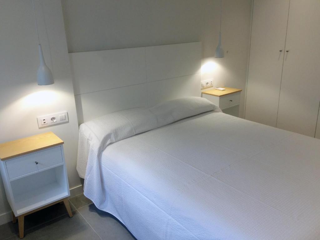 a bedroom with a white bed and two night stands at Apartamentos Angelito Playa América B in Nigrán