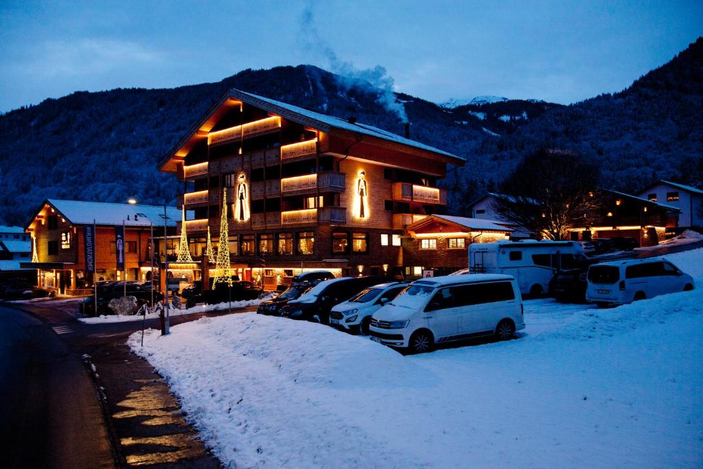 a large building with cars parked in the snow at Hotel Die Montafonerin in Vandans