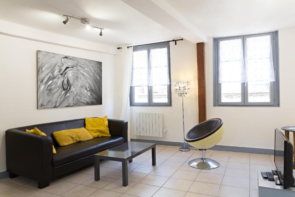 a living room with a black couch and yellow pillows at Appartement Moderne in Honfleur