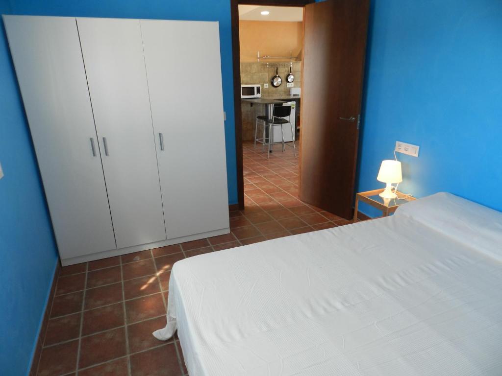 a bedroom with a white bed and a kitchen at DADA CAÑOS in Los Caños de Meca