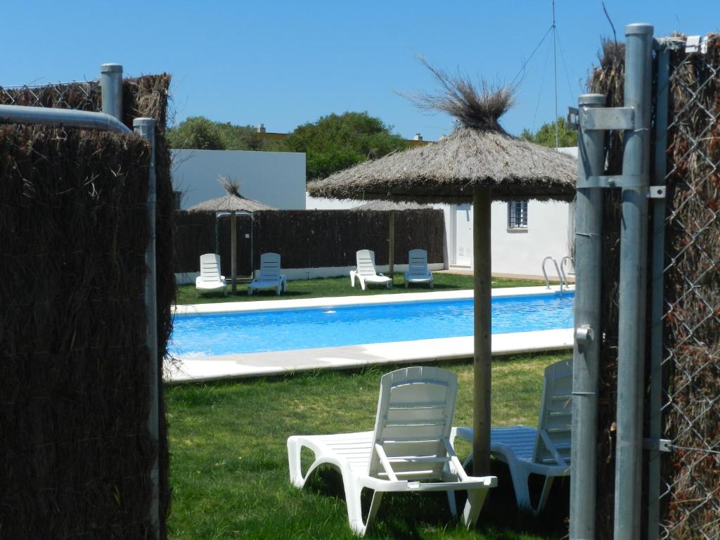 two chairs and an umbrella next to a swimming pool at DADA CAÑOS in Los Caños de Meca
