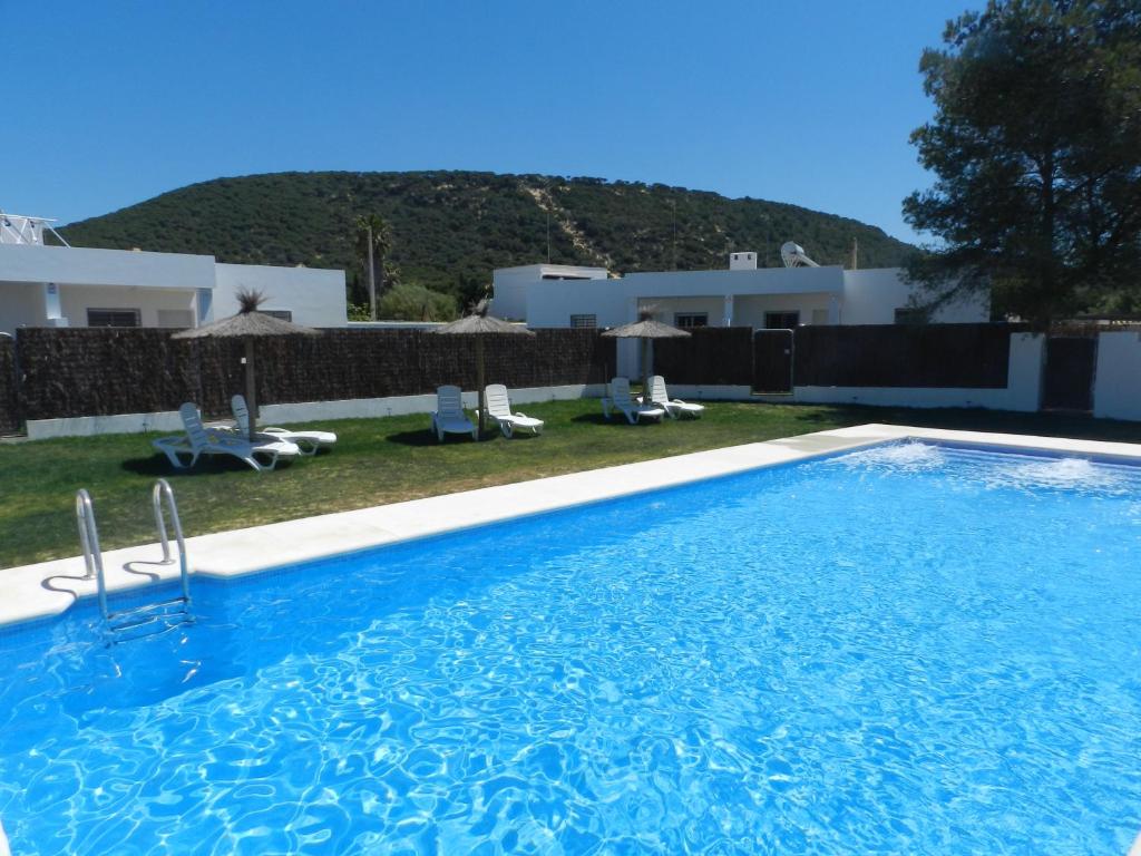 a large swimming pool with chairs and a house at DADA CAÑOS in Los Caños de Meca