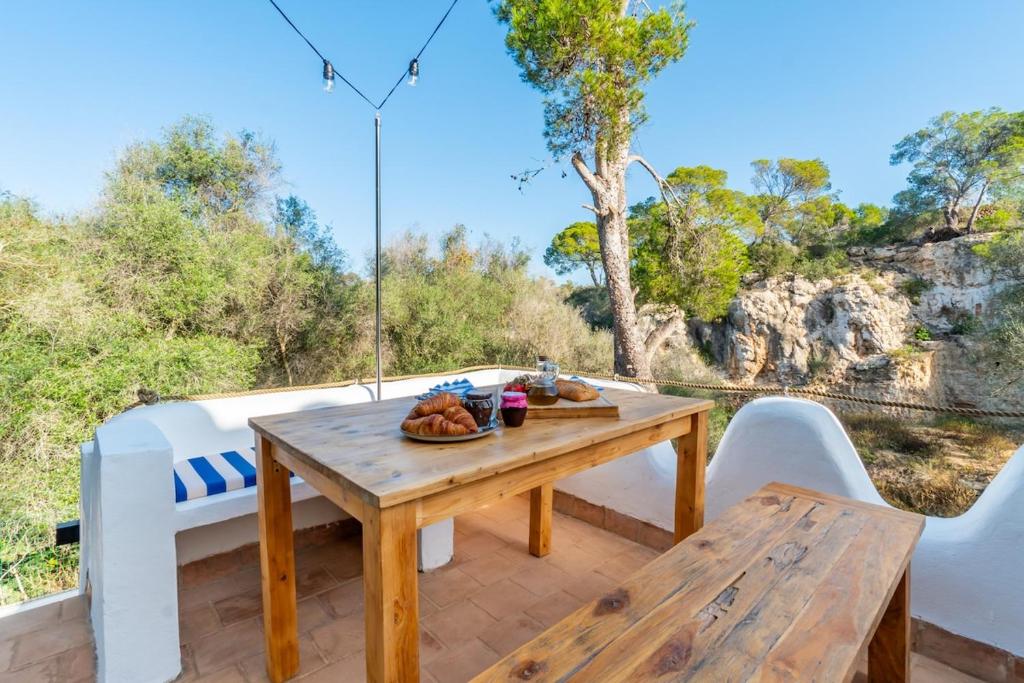 a wooden table and chairs on a patio with a table at Casa Tuna - Beach 100m - Cala Llombards in Santanyi
