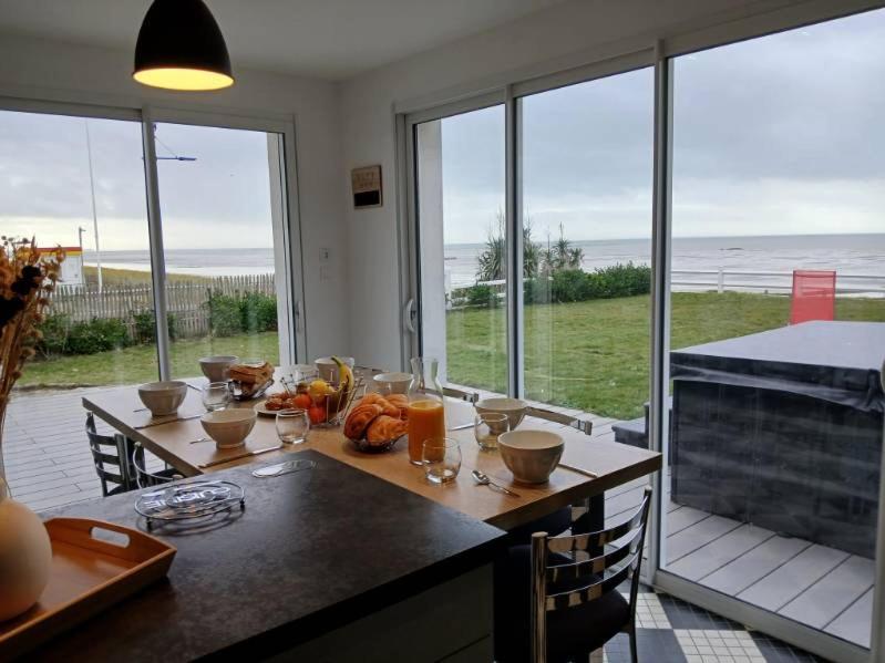 une salle à manger avec une table avec vue sur l'océan dans l'établissement La Maison de la plage, à Hauteville-sur-Mer