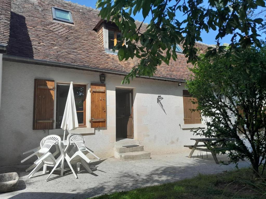 dwa krzesła i parasol przed domem w obiekcie Agréable et jolie maison avec grand jardin w mieście Pellevoisin
