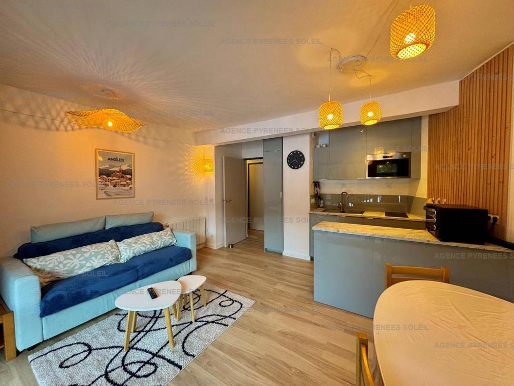 un salon avec un canapé bleu et une cuisine dans l'établissement Appartement F2/cabine pieds des pistes avec balcon, parking privé et accès internet - Les Angles - FR-1-295-197, aux Angles