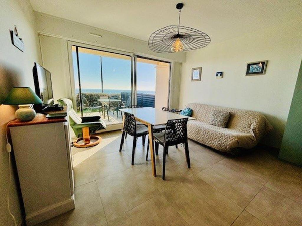 un salon avec une table, des chaises et un canapé dans l'établissement Quiberon : 2 pièces avec jardin privé, terrasse et parking à 2 pas de la côte - FR-1-478-299, à Quiberon