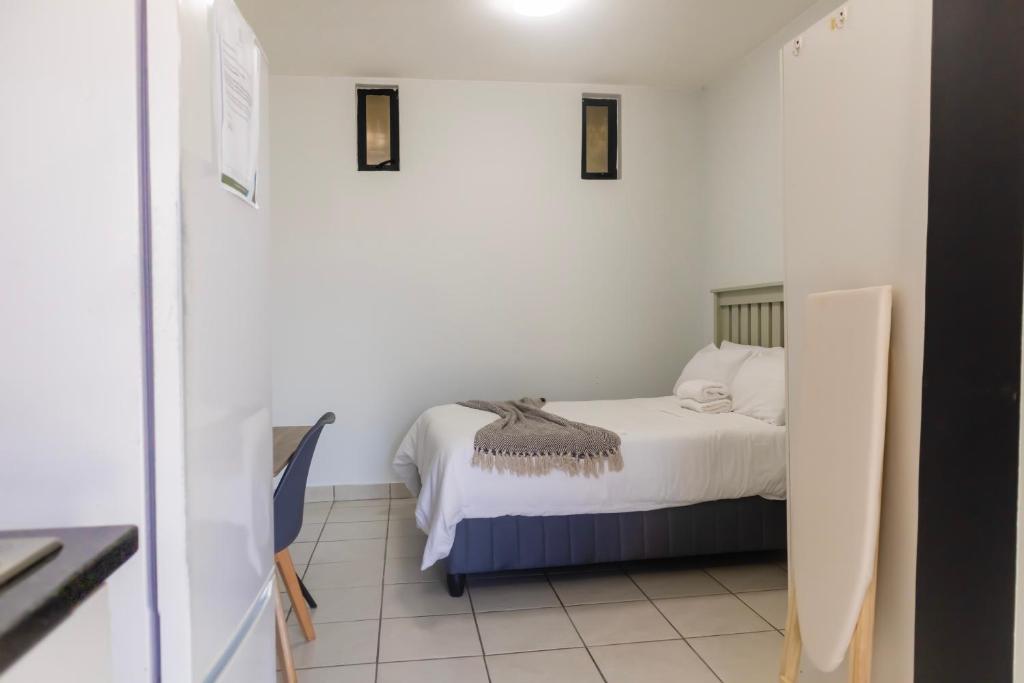 Un dormitorio pequeño con una cama con sábanas blancas. en Grace Villas 28, en East London