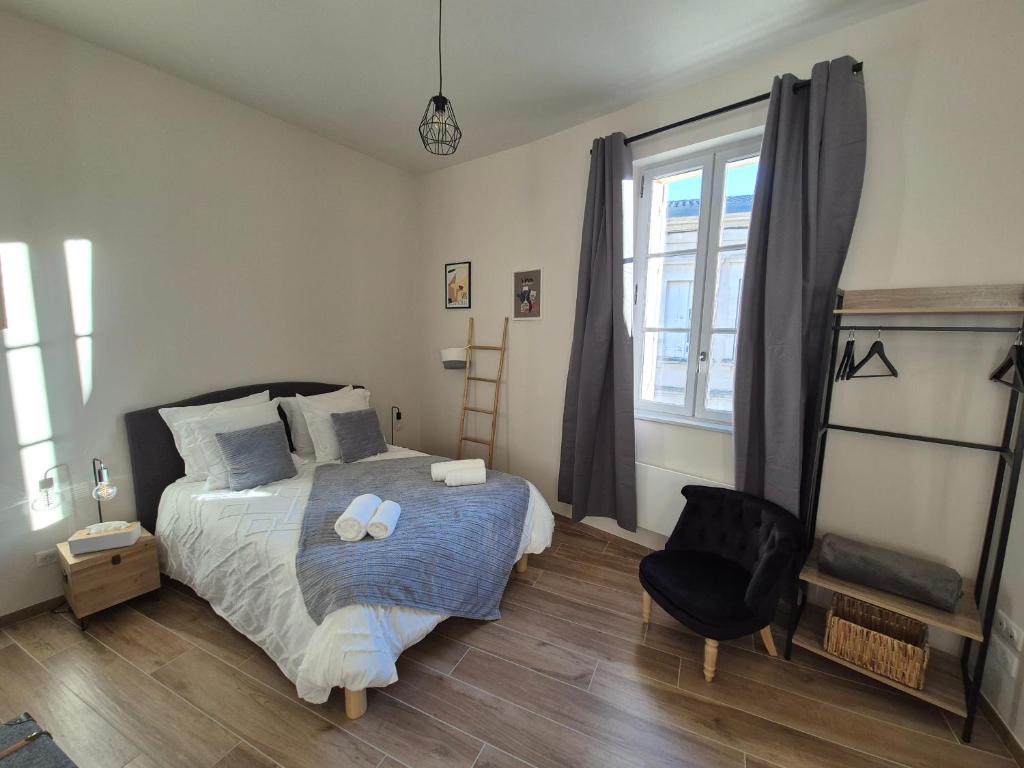 a bedroom with a bed and a chair and a window at Le Studio des "Caves de la Tour du Roy" in Saint-Émilion
