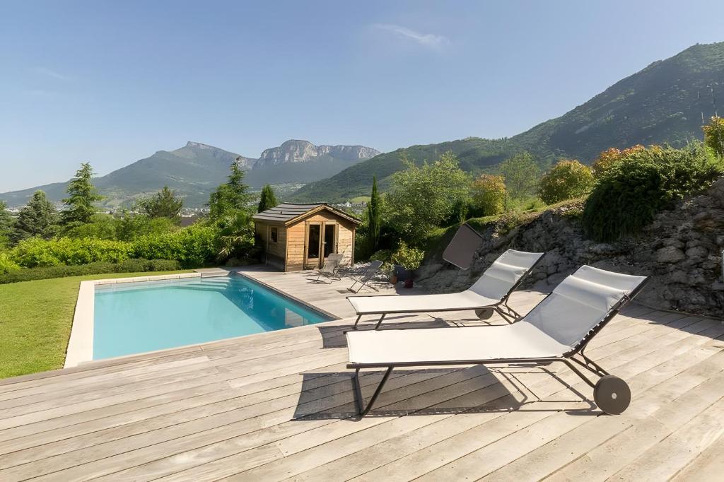 a pair of white chairs sitting next to a swimming pool at Le Gypaete - Challes Les Eaux in Challes-les-Eaux