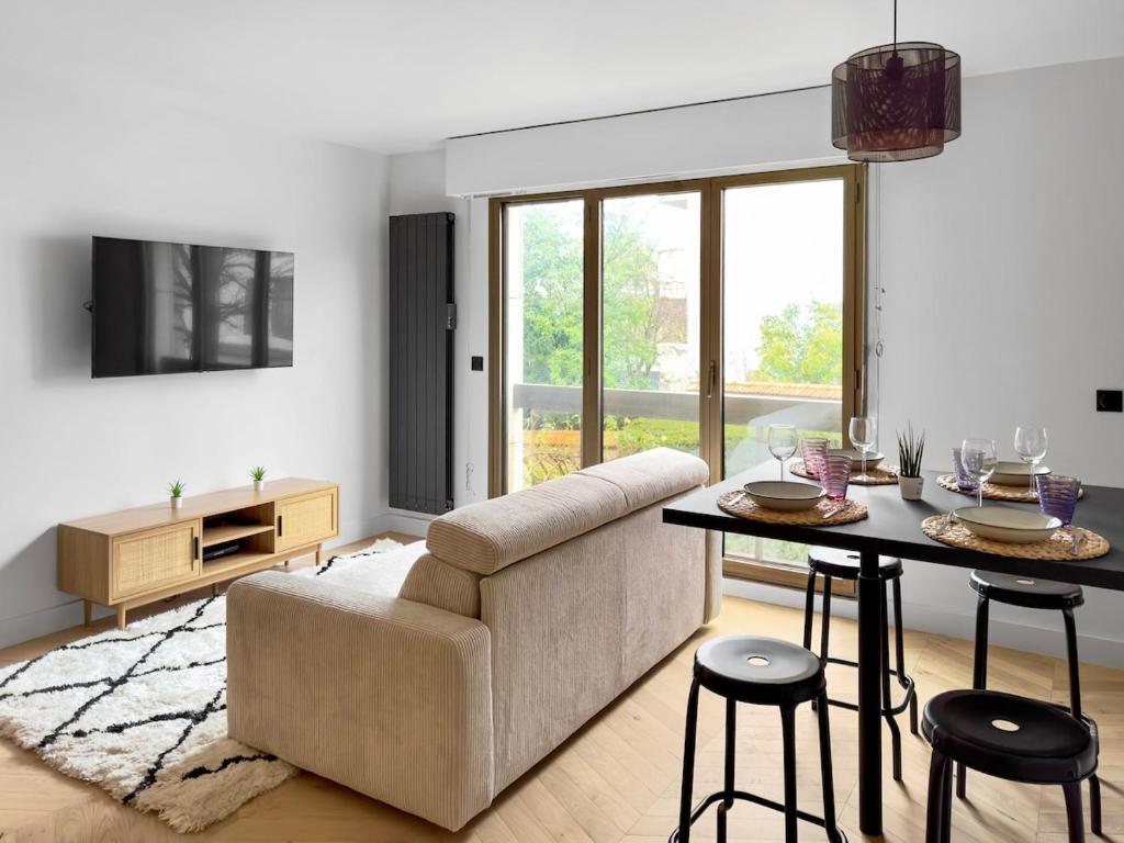 un salon avec un canapé et une table dans l'établissement Charmant Appartement Neuilly - 10mn Champs-Elysées, à Neuilly-sur-Seine