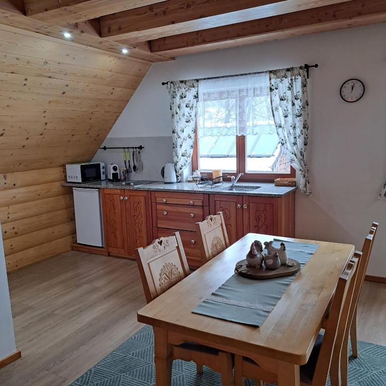 a kitchen and dining room with a wooden table and chairs at Apartamenty Ancymon in Węgierska Górka