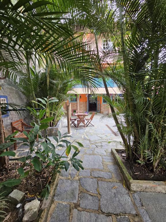a patio with palm trees and a table and benches at Hospedaria do Engenho in Niterói