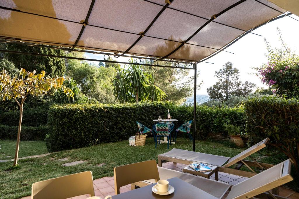 a patio with a table and chairs under an umbrella at La Résidence du Bailli in Rayol-Canadel-sur-Mer