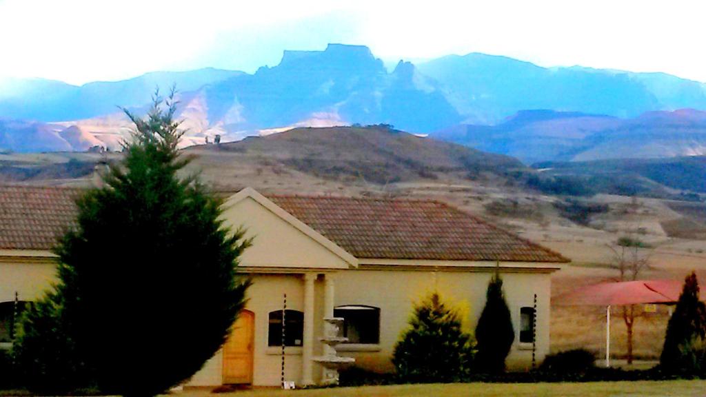 uma casa branca com uma montanha ao fundo em River Crossing em Champagne Valley