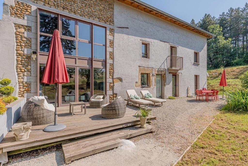 une maison dotée d'une terrasse avec un parasol et des chaises dans l'établissement Completely renovated old farmhouse in Drome, à Saint-Bonnet-de-Valclérieux