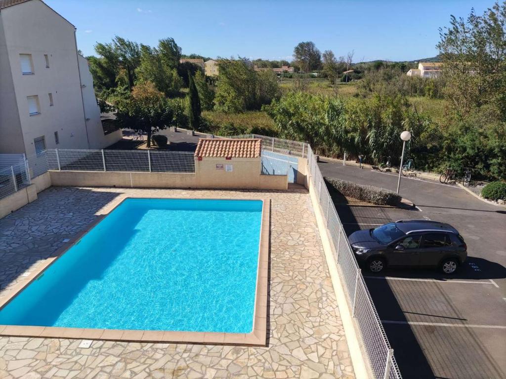 une piscine avec une voiture garée à côté d'un bâtiment dans l'établissement Appartement 2 pièces mezzanine climatisé avec piscine et parking privé à Marseillan - FR-1-326-789, à Marseillan