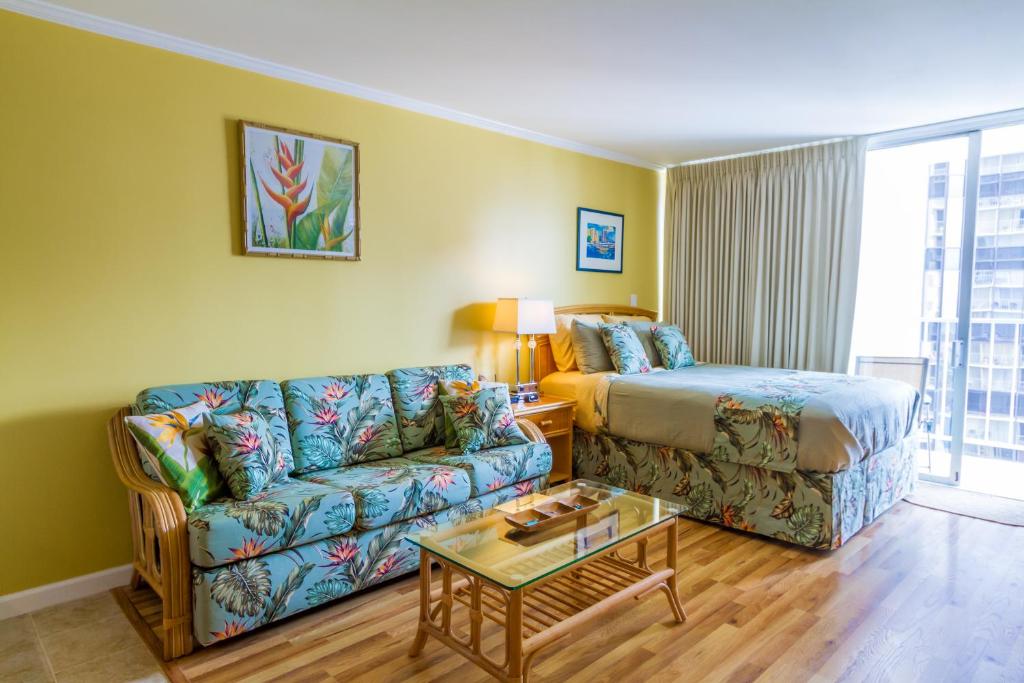 ein Wohnzimmer mit einem Sofa und einem Bett in der Unterkunft Tropical Studios at Marine Surf Waikiki - FREE PARKING - BEST LOCATION - FULL KITCHEN - SWIMMING POOL in Honolulu